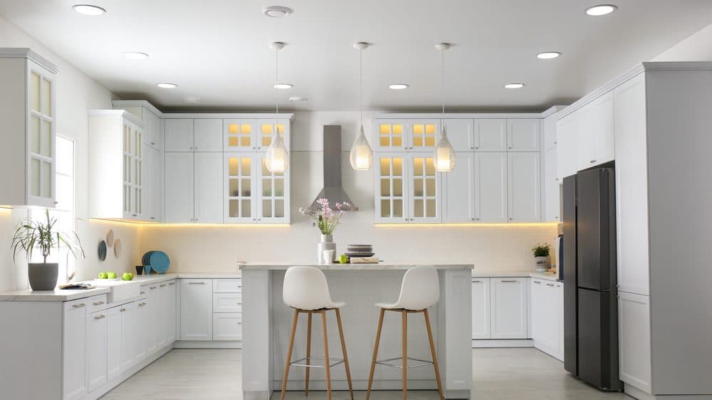 Three modern pendant lights flickering above a clean white kitchen island.