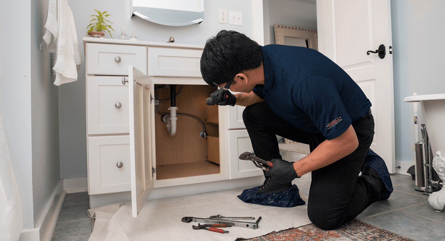 Man looking at the drain under a bathroom sink