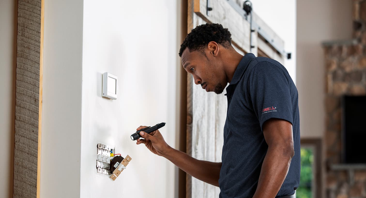 A professional Snell electrician using a flashlight to safely inspect and troubleshoot exposed residential wall switch wiring during an electrical repair service.