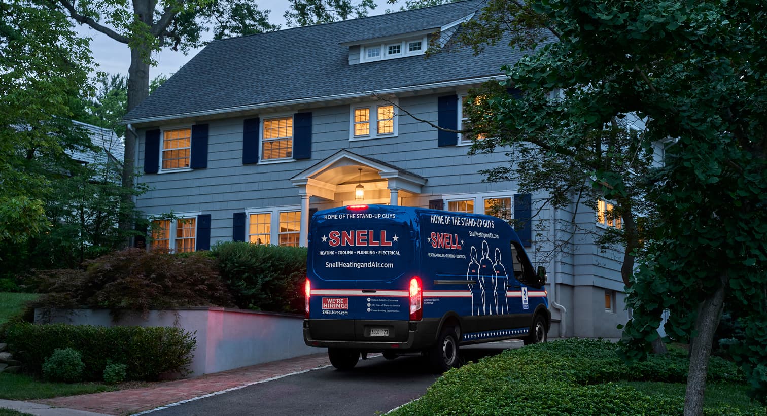 A Snell service van parked in a residential driveway at night, arriving to provide emergency electrical services.