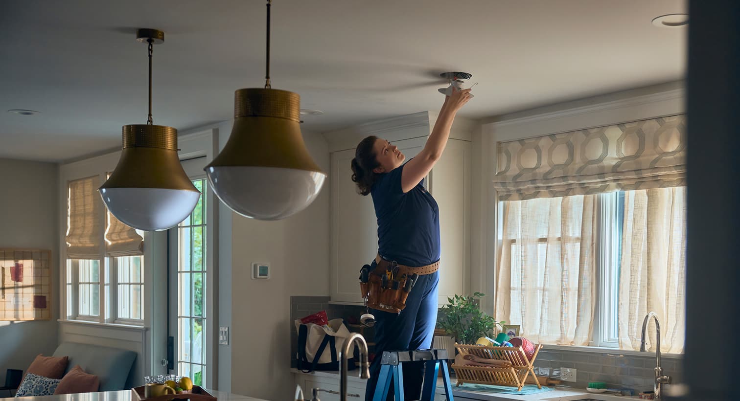 A professional Snell electrician standing on a ladder to install modern recessed ceiling lights during a residential electrical installation service.