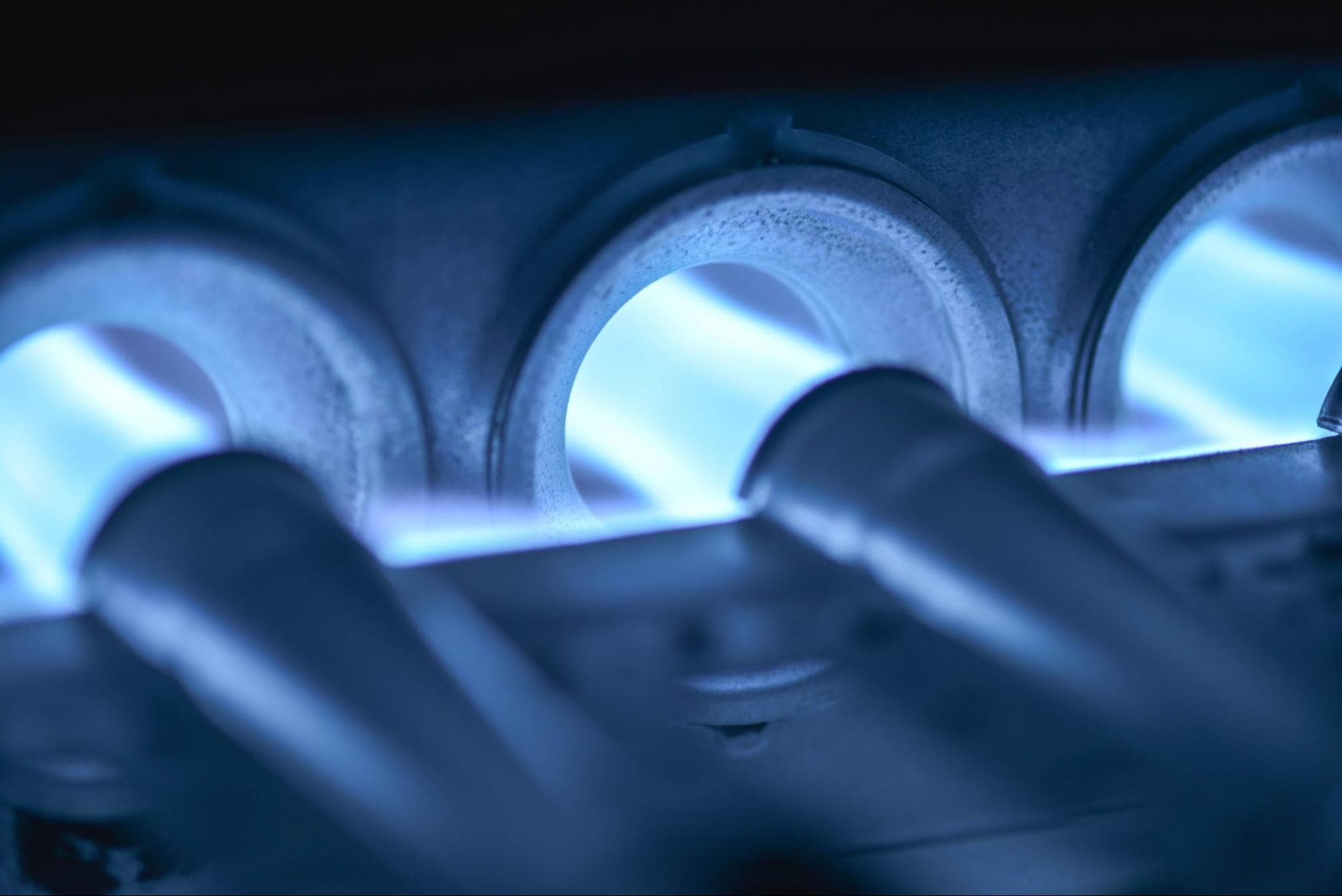 A close-up photograph of three gas furnace inshot burner tubes.