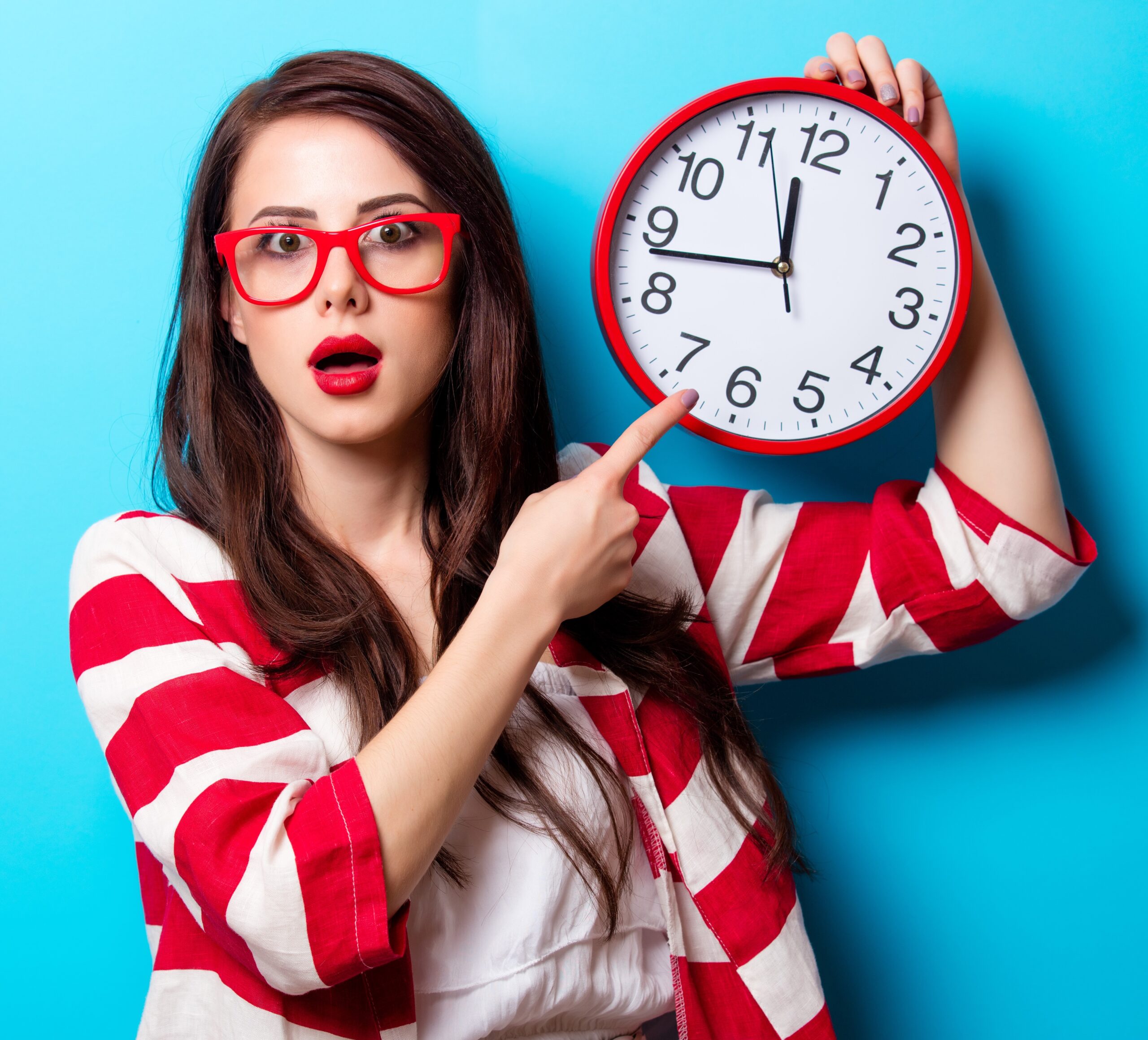 Young woman looking surprised with a clock